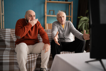 Upset elderly father and middle-aged son football fans disappointed by team losing match on TV