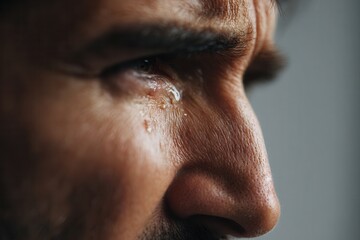 Close-up adult white man crying with red swollen eyes and frustrated expression.