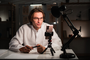 Male doctor blogger recording video using smartphone for social media followers during night shift