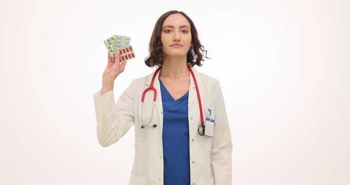 Woman family doctor in white coat holds pill blisters and glass of water. Medical specialist woman explains dosage reminding patient about therapy