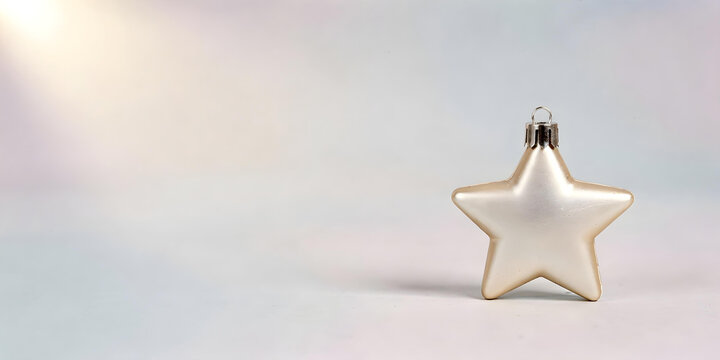 Single white matte glass Christmas ornament in the shape of a star, set against a light, slightly blurred background with a lens flare in the upper left corner.