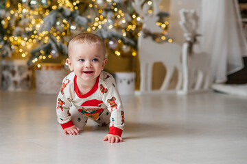 A one-year-old baby crawls on all fours, dressed in a New Year's outfit, crawling around a New Year's-decorated room, smiling. New Year and Christmas. Parenting. Family