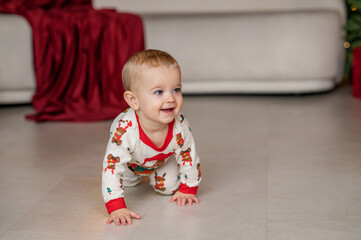 A one-year-old baby crawls on all fours, dressed in a New Year's outfit, crawling around a New Year's-decorated room, smiling. New Year and Christmas. Parenting. Family