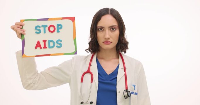 Woman doctor holds Stop AIDS board and colorful condoms. Serious specialist woman promotes safe sex education supporting HIV prevention slow motion