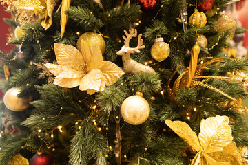 close up mini golden Christmas ornament decoration on snowy Christmas tree with red and yellows golden sparkle glitter ball 