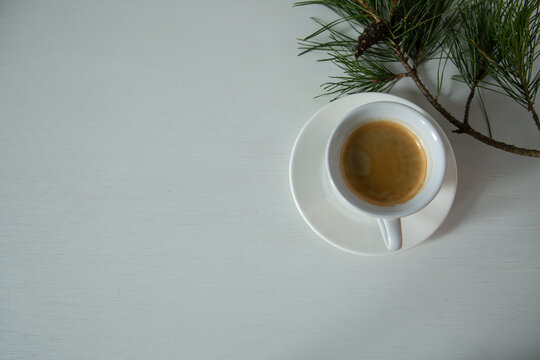 Morning cup of coffee and decor Christmas green tree with a pine cone. Ornament holiday background, creative design minimalism concept, white empty copy space. Flat top view. Natural day light