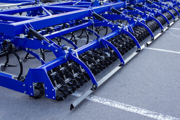Blue frame and numerous black rotating harrow disks of a modern agricultural cultivator or tillage...