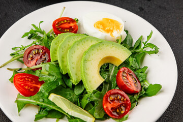 Avocado salad arugula, egg, tomato, mixed greens, vegetables dish fresh delicious gourmet food background tabletop rustic food top view copy space keto and paleo diet vegetarian food