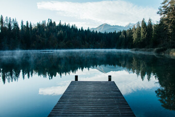 Misty Morning Lake with Wooden Dock and Mountain Reflections