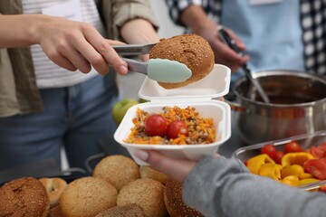 Volunteers giving food to homeless people in shelter, closeup