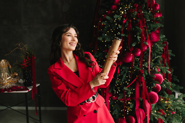 Woman holding festive cracker by New Year tree enjoying holiday fun.