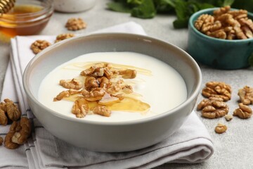 Delicious Greek yogurt with honey, nuts and mint on light grey table, closeup