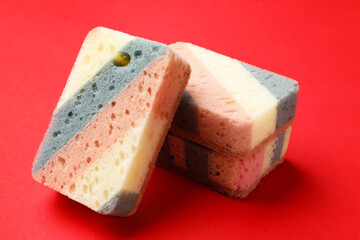 Colorful kitchen sponges on red background, closeup