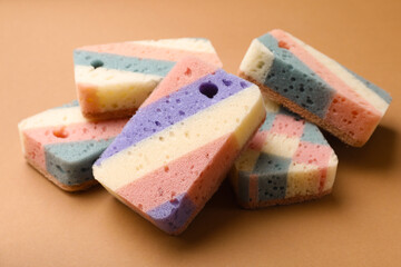 Colorful kitchen sponges on brown background, closeup