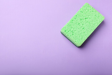 Kitchen sponge on violet background, top view. Space for text
