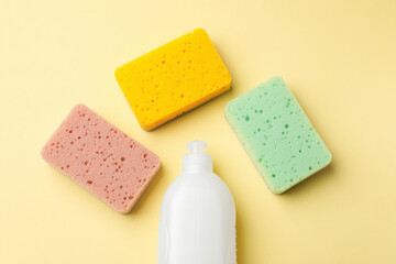 Kitchen sponges and dish soap on beige background, flat lay