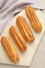 Fresh tasty eclairs on light table, top view