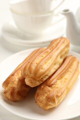 Tasty eclairs served on white table, closeup