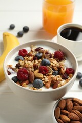 Healthy breakfast. Oatmeal with nuts, berries and milk on white wooden table, closeup