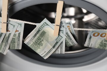 Banknotes hanging on clothesline near washing machine, above view