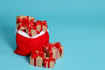 Santa Claus bag with Christmas gifts on light blue background, space for text