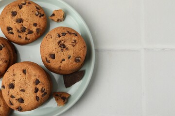 Delicious chocolate chip cookies on light tiled table, top view. Space for text