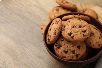Delicious chocolate chip cookies in bowl on wooden table, closeup. Space for text