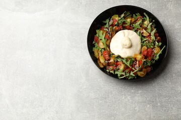 Delicious burrata cheese with arugula, tomatoes and dressing on light grey table, top view