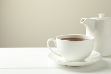Hot tea in cup and teapot on white wooden table. Space for text