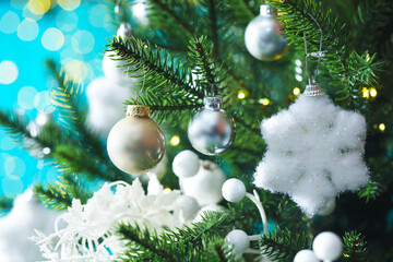 Beautiful ornament on Christmas tree against light blue background with blurred lights, closeup. Bokeh effect