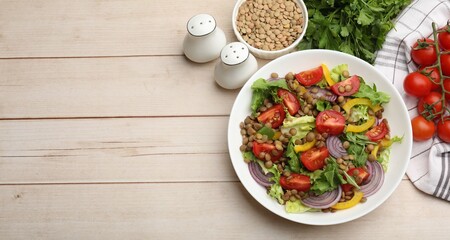 Naklejka premium Delicious lentil salad and ingredients on light wooden table, flat lay. Space for text