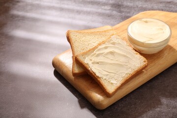 Bread slices with butter on grey table, closeup. Space for text