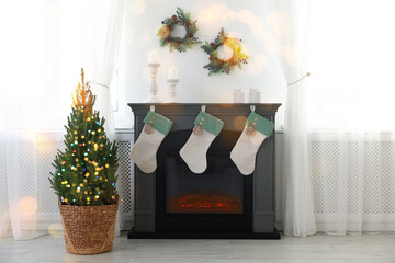 Potted small spruce tree and fireplace decorated for Christmas. Interior design
