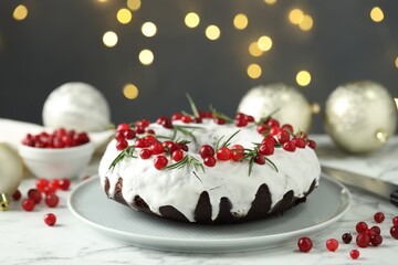 Tasty Christmas cake with cranberries on white marble table against blurred lights, closeup