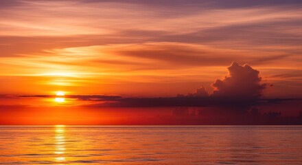 Fototapeta premium Vibrant orange sunset over calm ocean water with dark clouds.