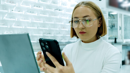 Professional female optician uses a tablet or phone to explain frame options