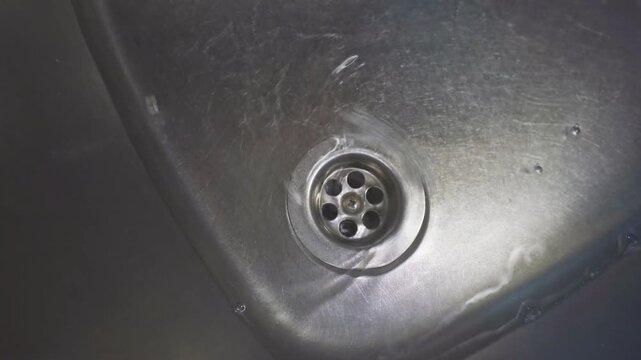 Water and soap flowing in steel sink