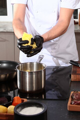 The cook in the kitchen holds sliced potatoes in his hands. Sliced potatoes in the hands of the cook. Cooking dishes from vegetables. Hands in protective glove