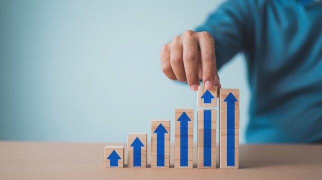 Hand stacking wooden blocks with growth arrows for stunning business success and financial performance