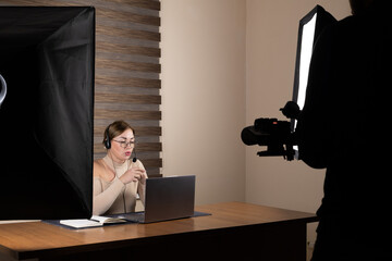 Female remote worker with a headset looking at a computer screen in a dark