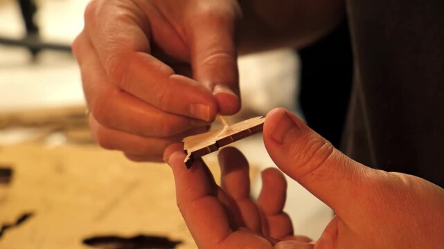 A man smears a wooden part with PVA glue in close-up. The creative process of creating DIY crafts. Gluing a world map from individual pieces of countries. Hobby concept. Carpentry. High quality 4K.