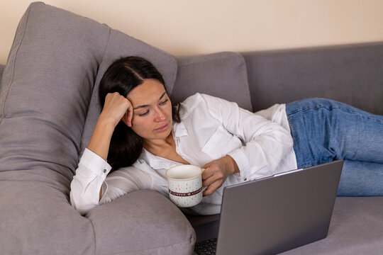 Woman relaxing on a couch while using her laptop to browse or work from home