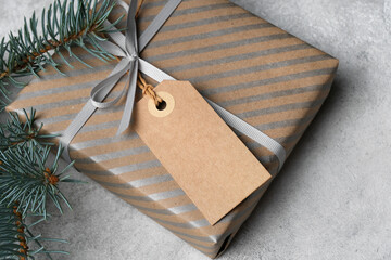 Blank carft Christmas gift tag mockup attached to a beautifully wrapped present with silver stripes and evergreen accents, copy space