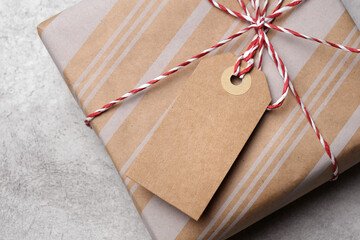 Gift package wrapped in brown paper with white stripes, tied with red and white twine, featuring a blank gift tag with copy space for personalization, ideal for special occasions and celebrations