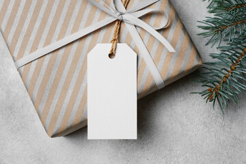 White Christmas gift tag mockup with copy space for design, featuring a textured surface, tied with...