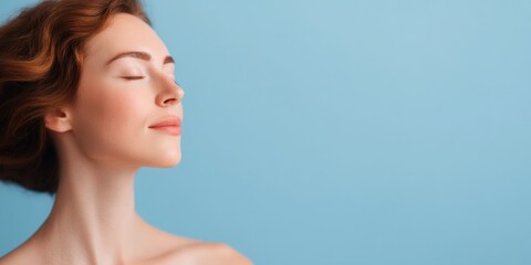 Naklejka premium A serene woman with closed eyes, smiling gently, exudes calmness against a soft blue background.