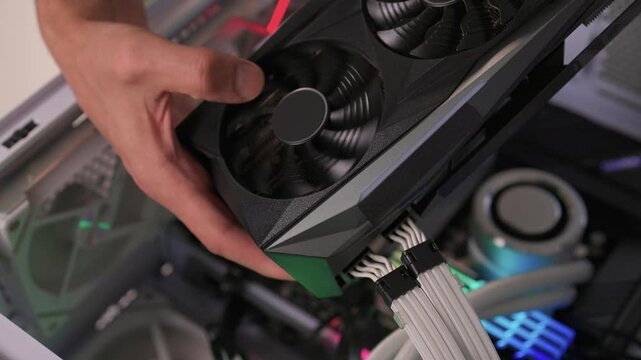 Building computer with careful assembly, Installing components with precise attention to detail, Assembling desktop computer featuring graphics card and lighting effects