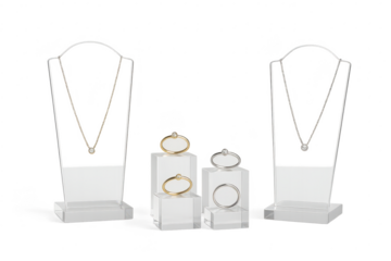 Diamond jewelry set with necklaces and rings displayed on transparent stands, isolated.