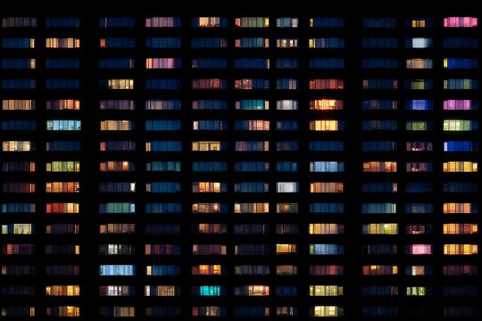 City apartment at night, windows glow with diverse lives