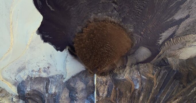 Pipe releasing muddy water and gravel at phosphate mining site during mineral washing and separation process.